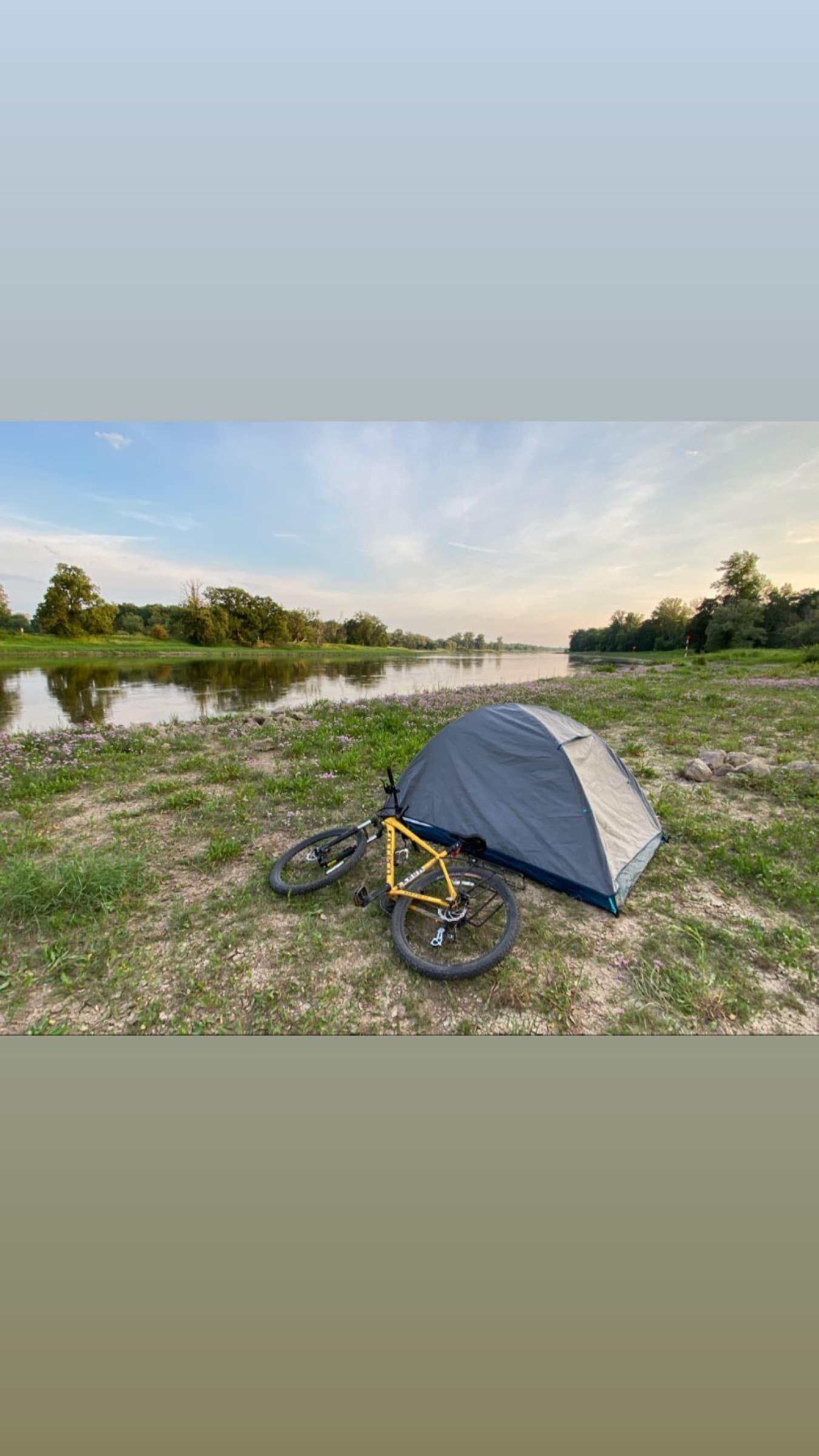 Namiot i rower nad rzeką.